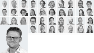 Collage of multiple black‑and‑white headshots of team members, with a larger portrait of a smiling man with glasses in the bottom-left corner.